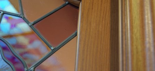 Detall talla en porta massissa de roure amb vitrall aplomat