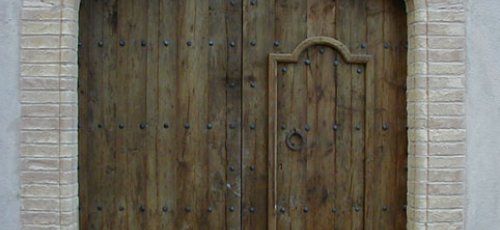 Porta de dos fulles grans i una de petita en fusta de pi vell i ferratges de forja
