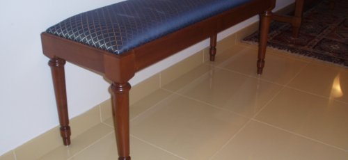 Banqueta tapizada con patas torneadas. Fabricada en madera de cerezo mcizo.