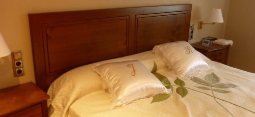 Dormitorio con cabezal plafonado y mesitas ventrudas con cajones. Fabricado en madera de cerezo macizo.