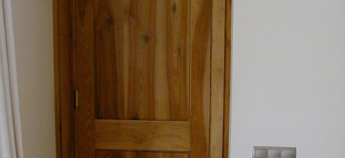 Puerta maciza de dos plafones en madera de nogal.